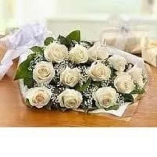 Wrapped bouquet of white roses with baby's breath lying on a wooden surface