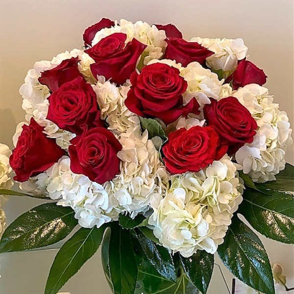 Arrangement of red roses and white hydrangeas in a clear glass vase