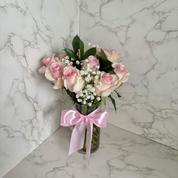 Pink roses in a glass vase with a pink ribbon