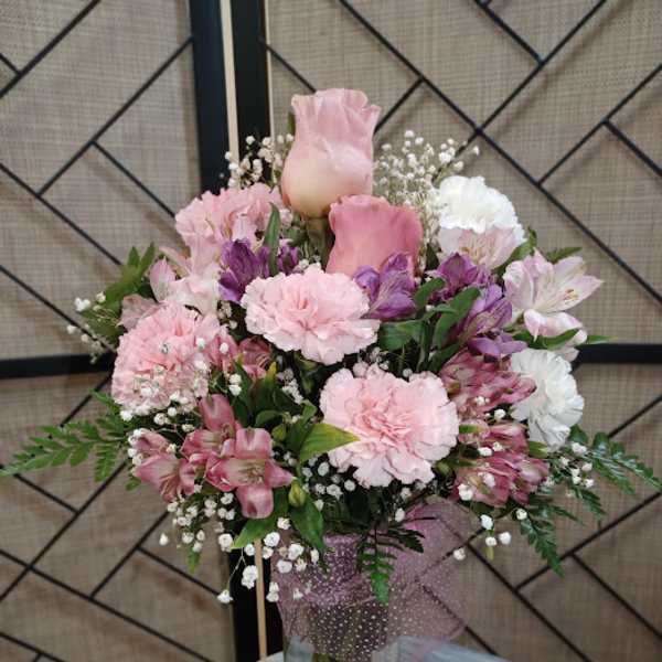 Pink and white bouquet in a glass vase with a small figurine beside it