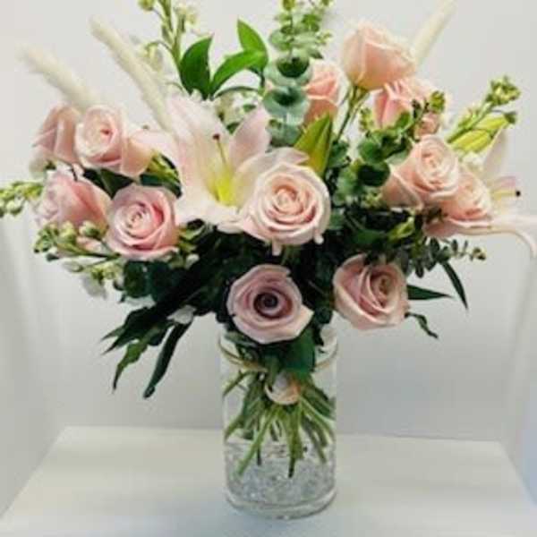 Pink roses and white lilies in a clear glass vase