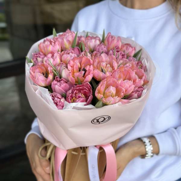 Pink tulip bouquet wrapped in pale pink paper and held by a person