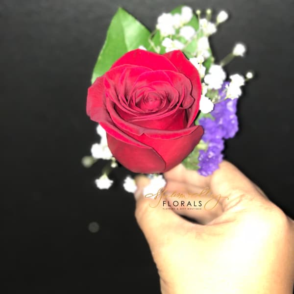 Single red rose with white baby's breath and purple filler held in hand