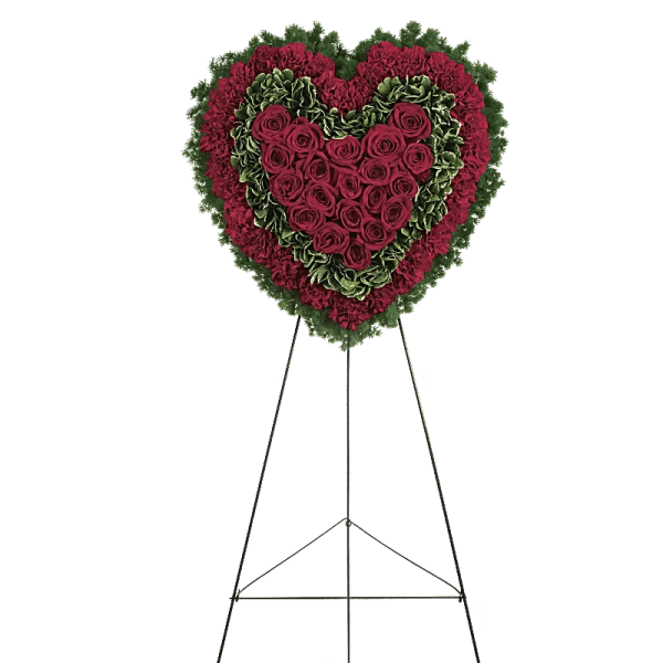 Heart-shaped floral wreath of red roses and carnations on a stand