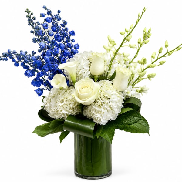 White roses and hydrangeas with blue and green orchids in a glass vase