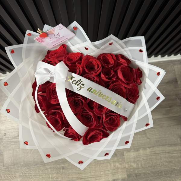 Heart-shaped bouquet of red roses wrapped in white paper with a ribbon