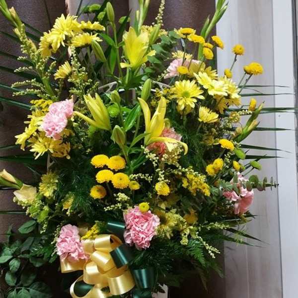 Large yellow and pink floral standing arrangement with ribbon