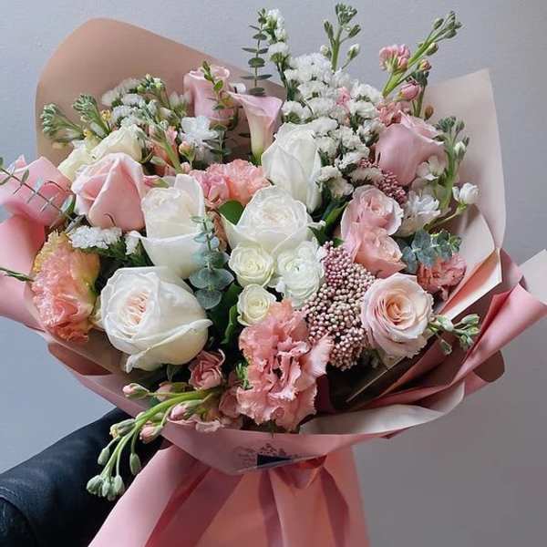 Hand-tied bouquet of pink and white roses with pink wrapping