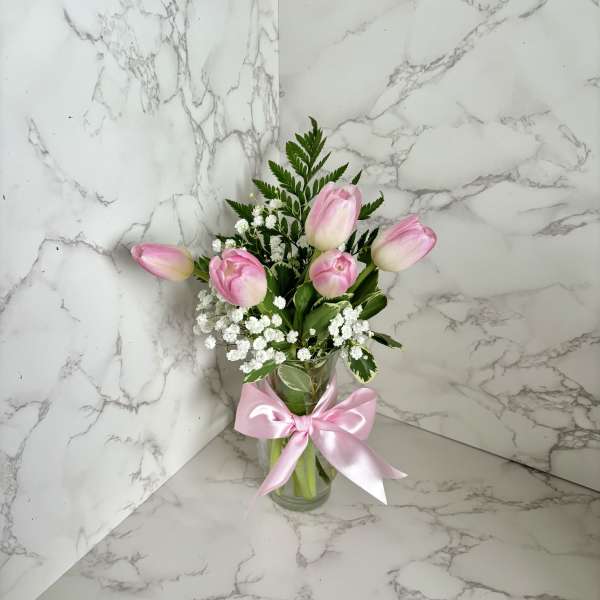Pink tulips in a glass vase with a pink ribbon