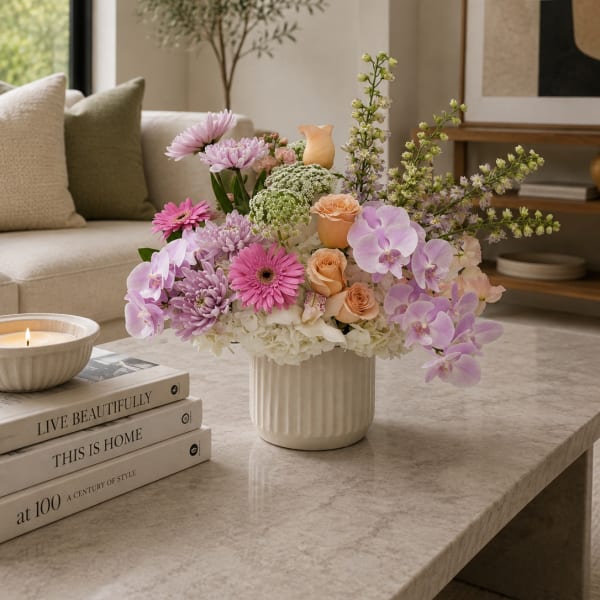 Pastel floral arrangement in a white vase with orchids, roses, and chrysanthemums