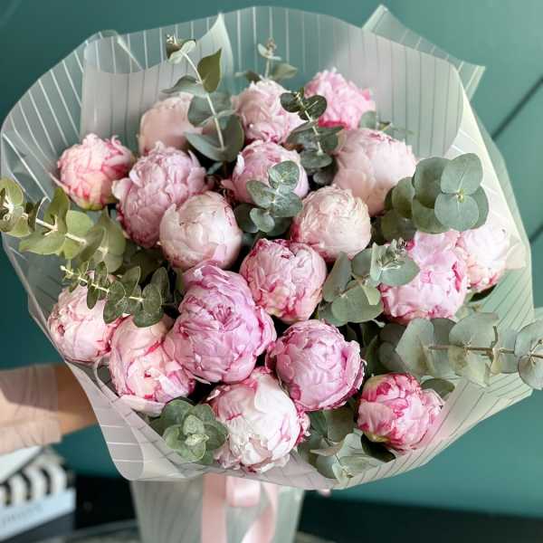 Bouquet of pink peonies with eucalyptus in striped wrapping
