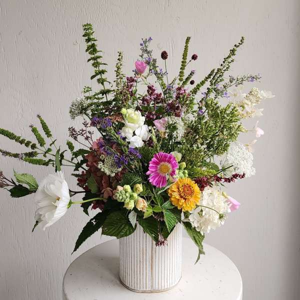 Mixed bouquet in a ribbed white vase with pink, white, yellow, and purple flowers