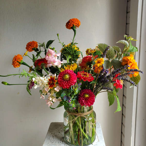 Mixed bouquet of bright flowers in a glass jar vase