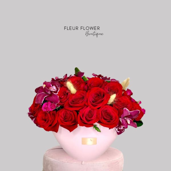 Red roses and purple orchids arranged in a pink vase