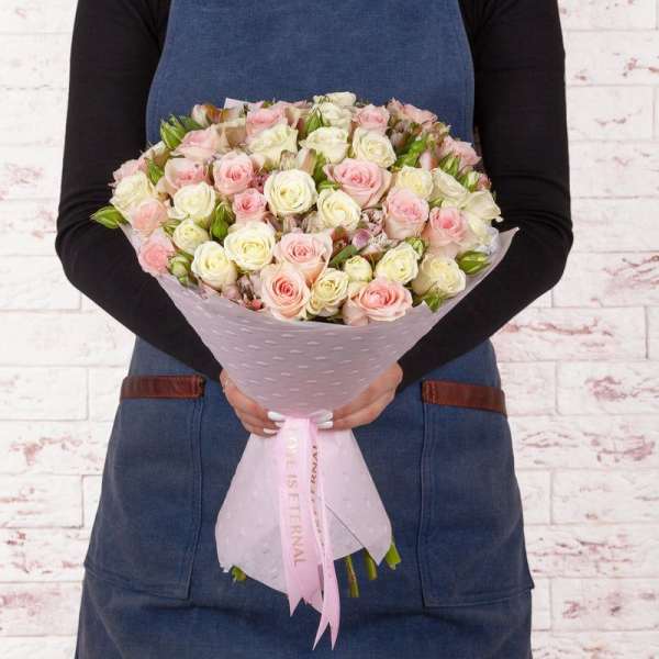 Bouquet of pale pink and white roses wrapped in pink paper