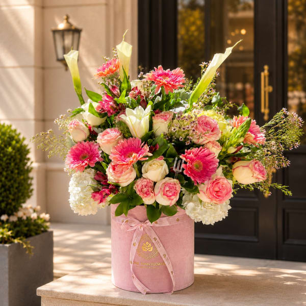 Pink and white mixed flower arrangement in a round pink box
