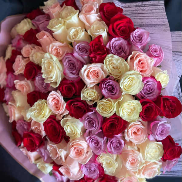 Large bouquet of red, cream, peach, and lavender roses wrapped in pastel paper