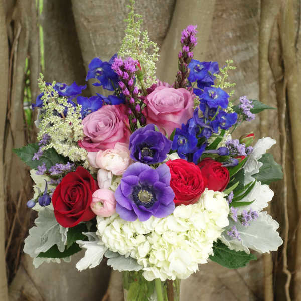 Mixed bouquet of roses, anemones, and hydrangea in a glass vase