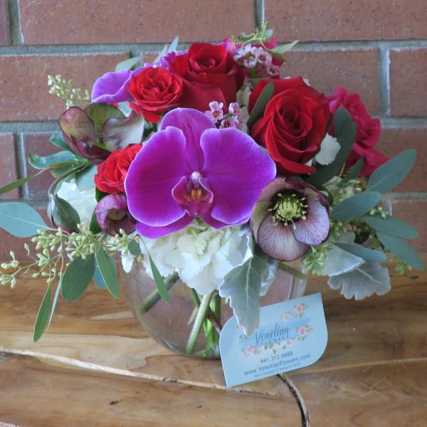 Bouquet of red roses and purple orchids in a glass vase