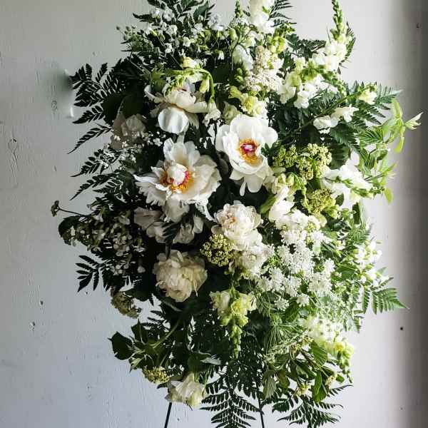 Large white floral standing spray with mixed greenery on an easel