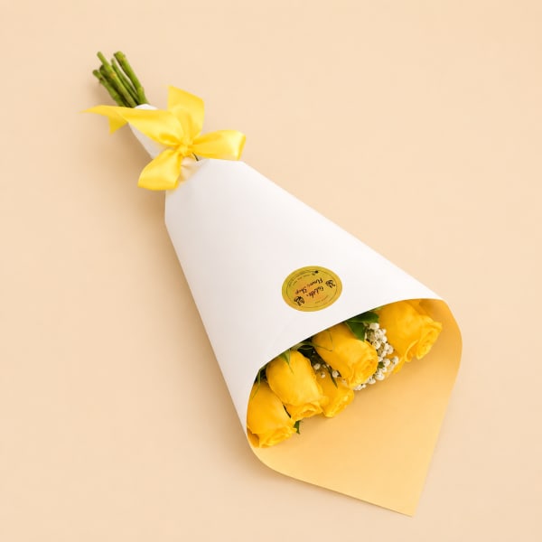 Bouquet of yellow roses wrapped in white paper with a yellow ribbon
