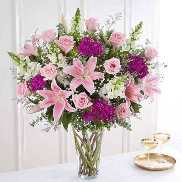 Pink lilies and roses arranged in a clear glass vase