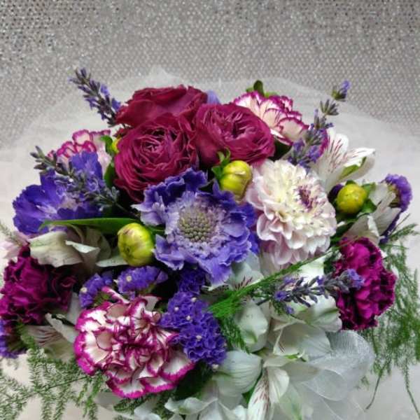 Bouquet of purple, pink, and white flowers wrapped in sheer fabric
