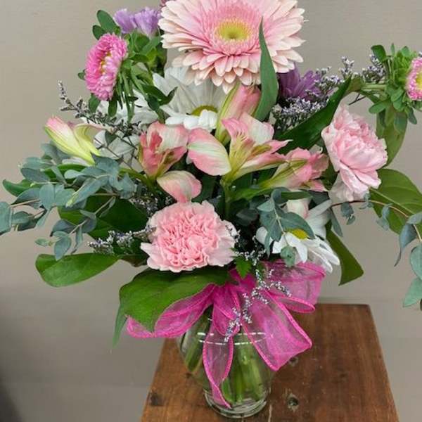 Pink and white mixed bouquet in a glass vase with a pink ribbon