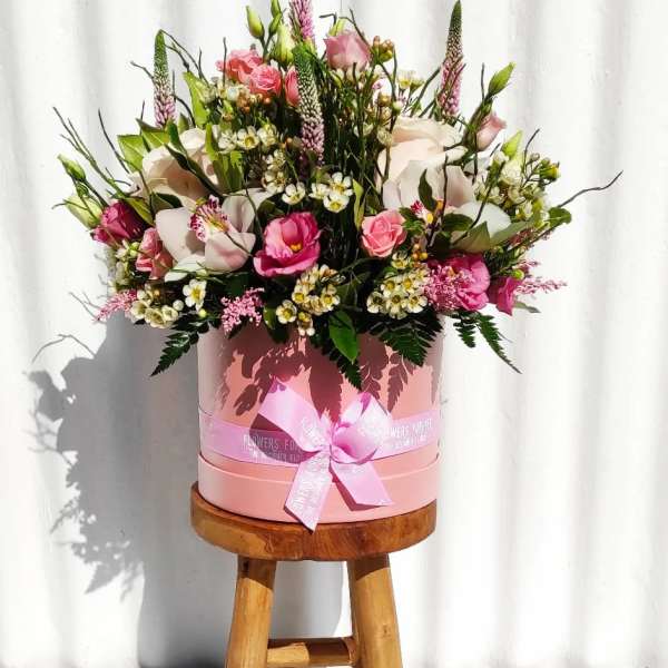 Pink and white mixed flower arrangement in a round pink box with ribbon