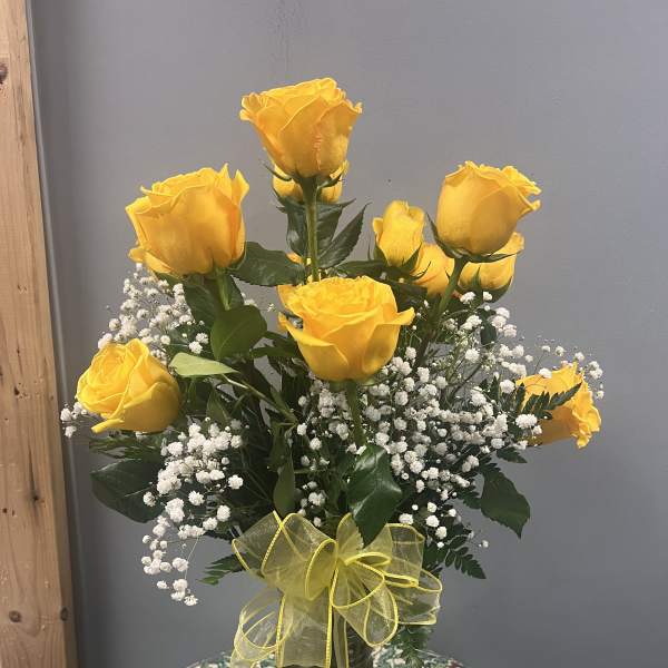 Yellow roses in a glass vase with baby's breath and a yellow ribbon
