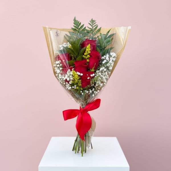 Bouquet of red roses wrapped in clear plastic with a red ribbon