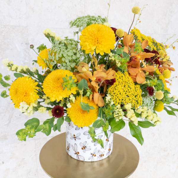 Yellow and orange floral arrangement in a patterned container