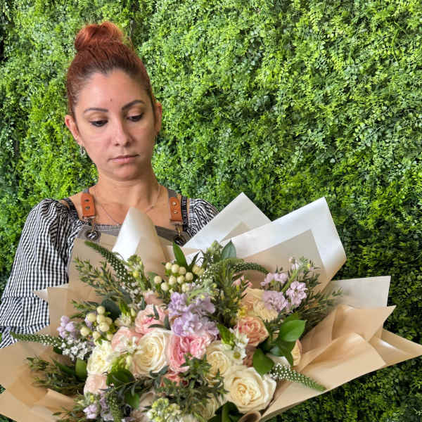 Woman holding a large bouquet of pastel roses and lilac flowers