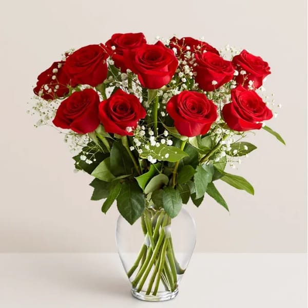 Red roses arranged in a clear glass vase with white baby's breath