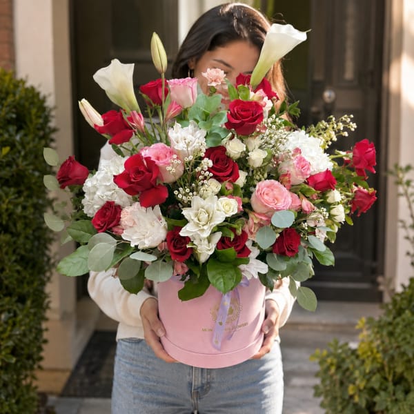 Large bouquet of red, pink, and white flowers in a pink hatbox