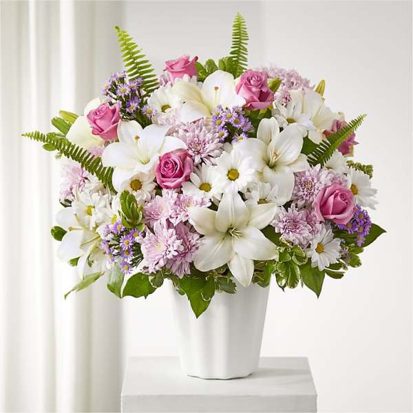 Pink roses and white lilies arranged in a white vase