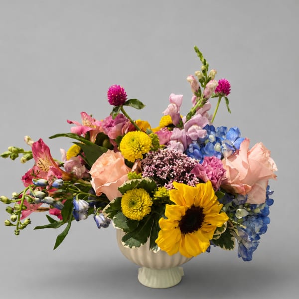 Colorful mixed flower arrangement in a cream vase