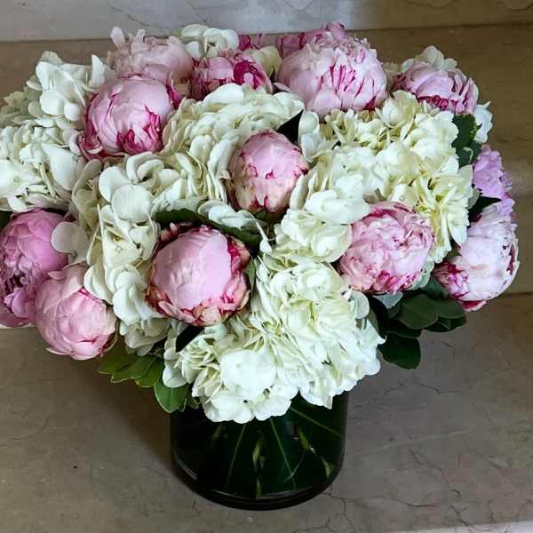 Pink peonies and white hydrangeas in a dark glass vase
