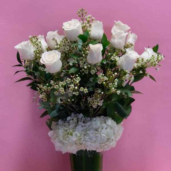 White roses and hydrangeas in a tall glass vase