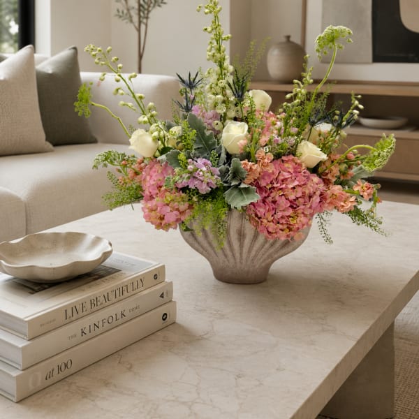Pastel floral arrangement in a textured vase on a coffee table