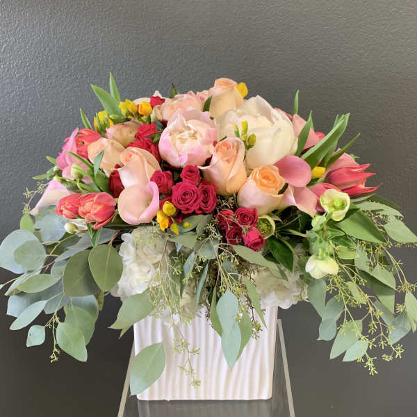 Large bouquet of pink and peach roses with white blooms in a white vase