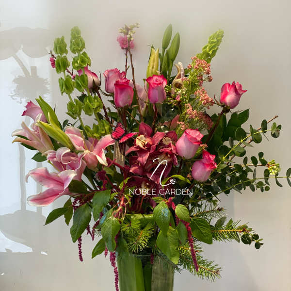 Tall mixed bouquet of pink roses and lilies in a glass vase