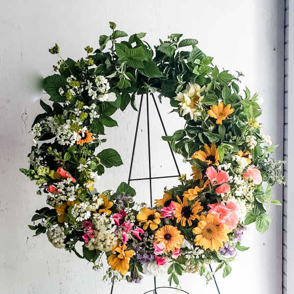 Large floral wreath with mixed blooms on a black stand