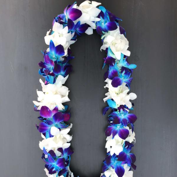 A purple, blue, and white flower lei on a dark background