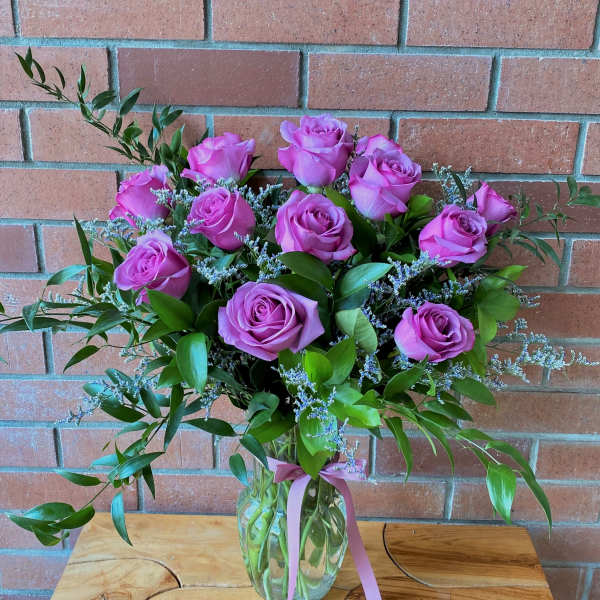 Pink rose bouquet in a clear glass vase with a ribbon