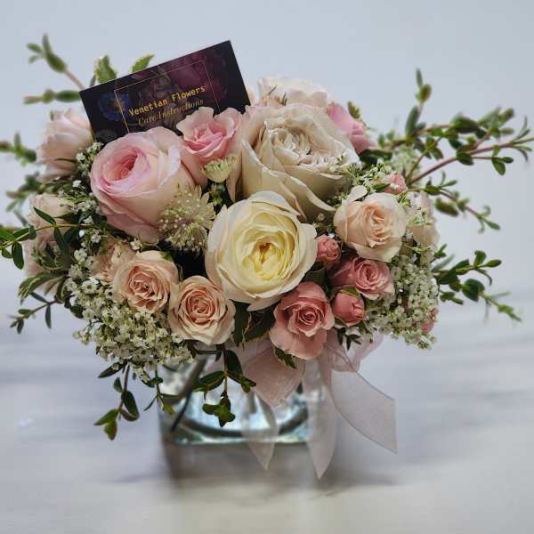Pink and cream rose bouquet in a glass vase with a ribbon