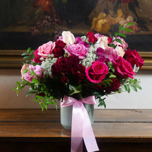 Bouquet of pink and red roses in a gray vase with a pink ribbon