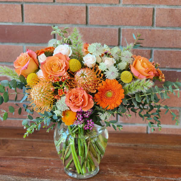 Bouquet of orange and peach flowers in a clear glass vase