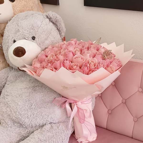 Pink rose bouquet held by a large gray teddy bear