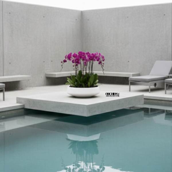 Pink orchid arrangement in a white bowl beside a pool